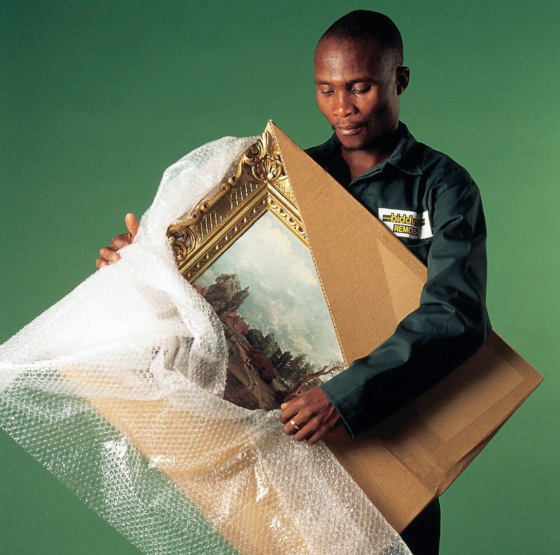 Professional packer wrapping framed oil painting with bubble wrap