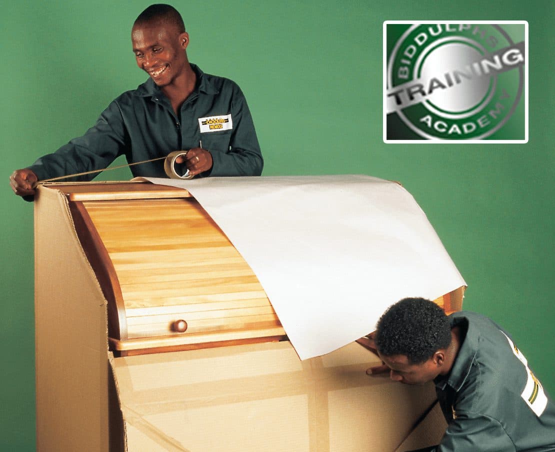 Biddulphs Training Academy staff wrapping a roll-top desk with protective paper