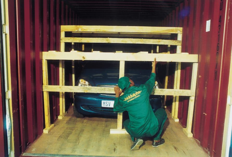 Vehicle secured inside shipping container with custom wooden crating